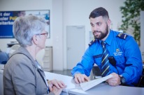 Ein Polizist der Kantonspolizei Basel-Stadt erläutert am Kundendesk einer Bürgerin ein Dokument.